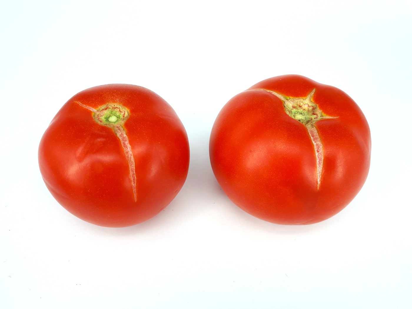 Two ripe tomatoes with long cracks radiating down from the stem end.